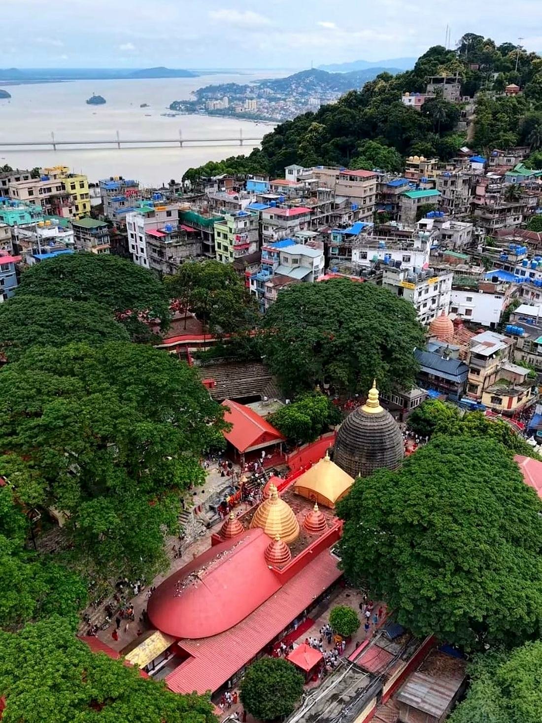 Aerial view of Kamakhya hill: Maa Kamakhya Devalaya among the trees, with Kamagiri Nivas on the ridge 300 metres above it and the Brahmaputra beyond