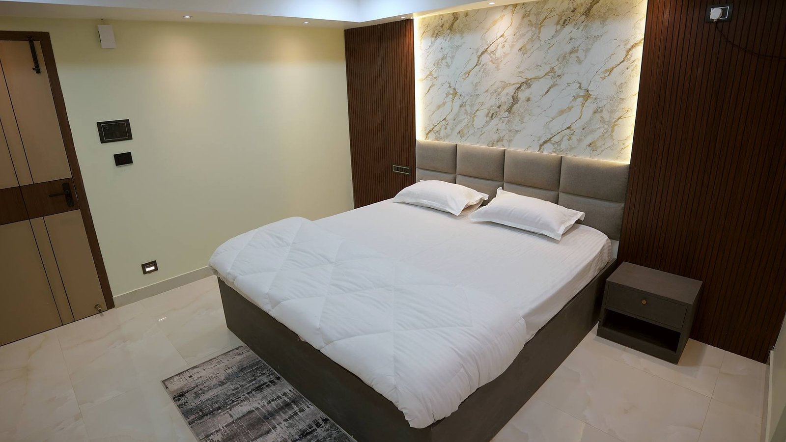A Deluxe Room at Kamagiri Nivas, its king bed set beneath a backlit marble panel