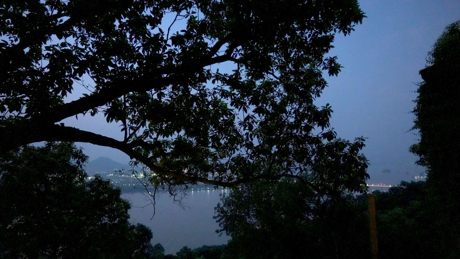 The Brahmaputra at dusk, the lights of Guwahati strung along the far bank